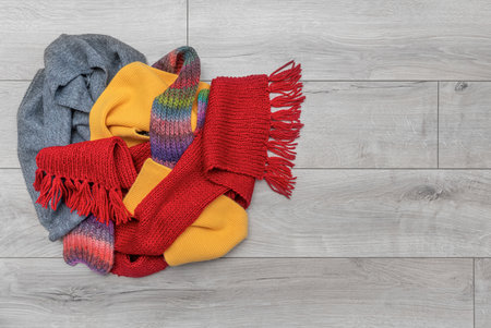Winter scarves lie in a pile on the floor.
