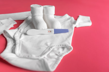Positive pregnancy test on the background of childrens clothing.の写真素材