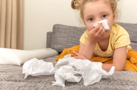 The child has a cold. He wipes his nose with a tissue.の写真素材