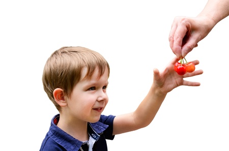 European boy 4-5 years old smiles and takes cherries from hands, images isolated on white