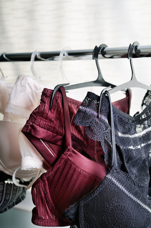 black, vinous and white lace lingerie hanging on the hanger front view verticalの写真素材