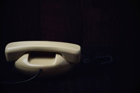 back of old-fashioned phone on a dark wooden background. horizontal format, toned imageの写真素材