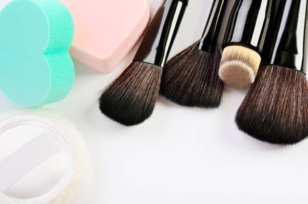Makeup brushes, sponges heart shape and powder puff on a white background horizontal, space for text
