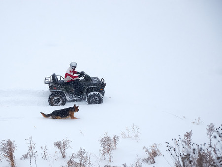 man riding ATV in the winter with a dog