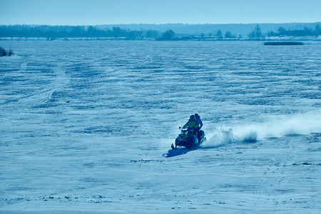 two people riding on a snowmobile on the frozen lake