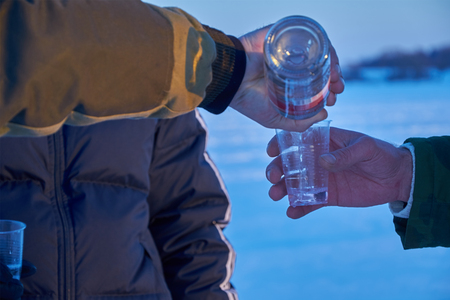 man pours vodka into a plastic Cupの写真素材