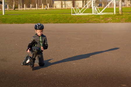 Boy roller-skating on the street with his back to the audience