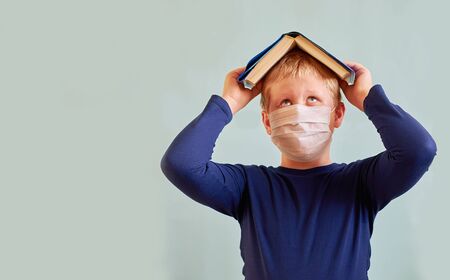 European in a white medical mask puts an open book on his head and looks upの写真素材