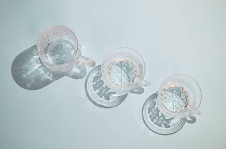 three clear crystal cups with handles stand in a row on a blue background, the view from the topの写真素材