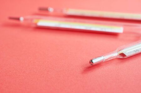 three medical thermometers lie on a red backgroundの写真素材