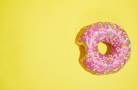 Pink donut lies on a yellow background. The view from the topの写真素材
