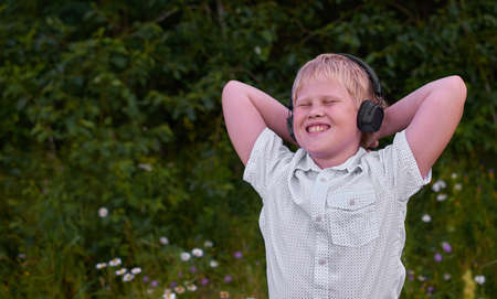 A smiling boy with headphones and walks in the Park in the summer