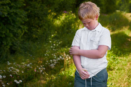 Sad boy walks in the park in the summerの写真素材
