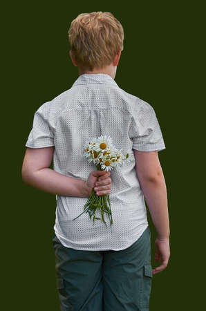 The boy hides a bunch of daisies behind his back. Back view on a uniform backgroundの写真素材