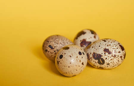 Four quail eggs lie next to each other on a yellow background close upの写真素材