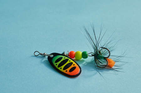 Fishing equipment. One multi-colored fishing lure with a hook close-up on a blue background
