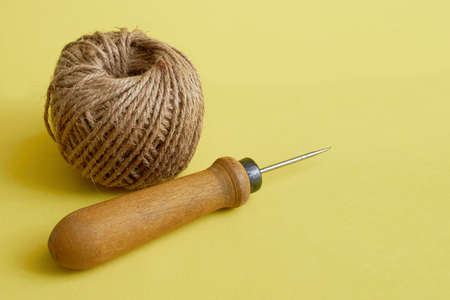 Sewing supplies. Awl and twine close up on a yellow backgroundの写真素材
