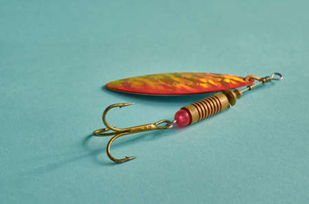 Bright orange fishing lure close-up on a blue background