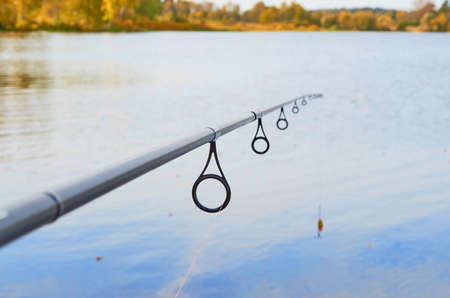 Rings on a fishing rod with a fishing line threaded through them and a lure close-up on the background of waterの写真素材