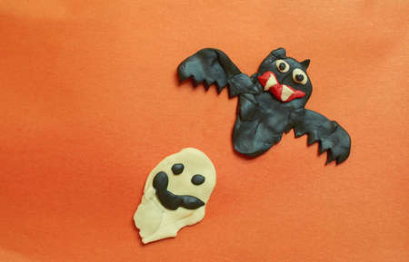Children's crafts made of plasticine. Halloween. Bat and Ghost on an orange backgroundの写真素材