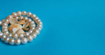 Marine layout. Pearl beads and lots of small shells on a blue background. Space for textの写真素材