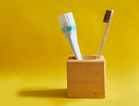 Wooden toothbrush and a tube of toothpaste in a wooden standの写真素材