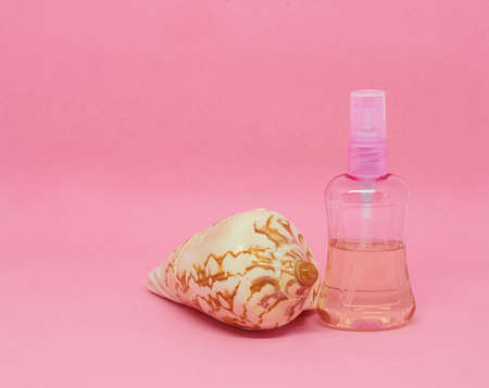A spray bottle filled with liquid and a seashellの写真素材