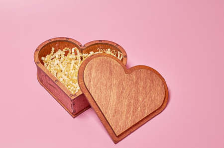 Wooden gift box in the shape of a heart with paper filling with an open lid. Side view Mock up.