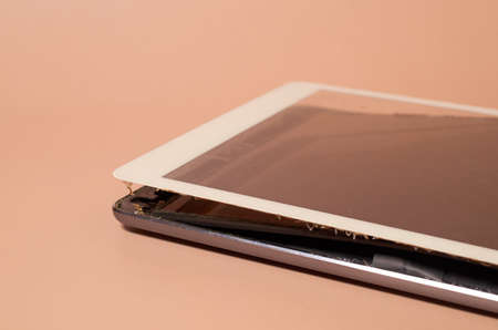 A broken tablet with a swollen battery and a dirty screen on a monochrome background, close up