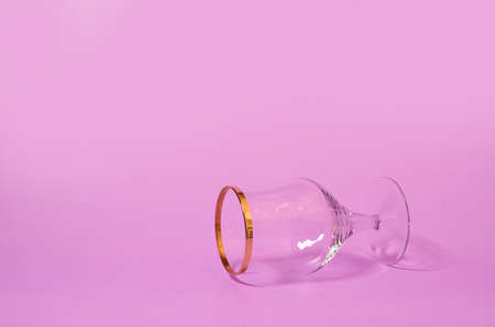 An empty wine glass lies on its side on a pink background. copy spaceの写真素材