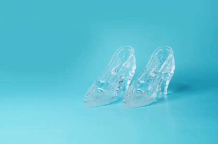 A pair of souvenir crystal shoes on a blue background. copy space, side viewの写真素材