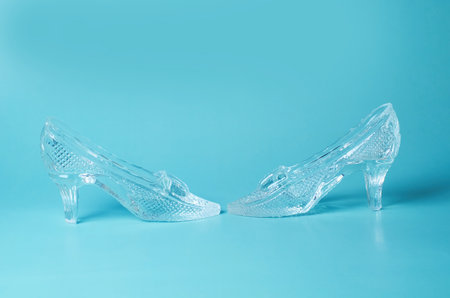 A pair of souvenir crystal shoes on a blue background. Space for textの写真素材