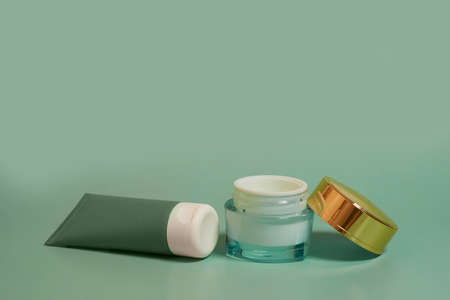 An open jar of face cream, a tube of hand cream on a colored background. Side view, mockup, mockup, templateの写真素材
