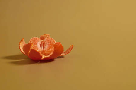Half a peeled tangerine and peel on a colored background, free space for text, close upの写真素材