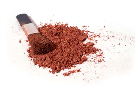 cosmetics. Scattered light brown eye shadow and makeup brush isolated on a white background. close...
