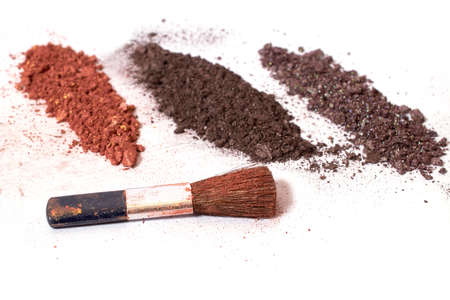 cosmetics. Scattered multicolored eye shadow and makeup brush isolated on a white background....