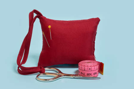 Mock up. A needle pad, scissors and a tailor's meter on a blue background