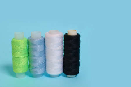 Coils with black, white, blue and green threads on a blue background. copy spaceの写真素材