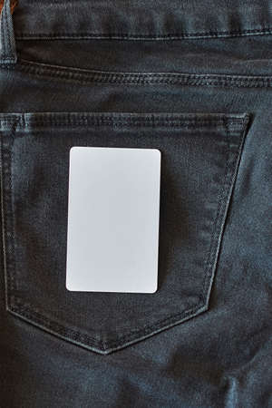 The upper part of old worn black jeans with pockets and a white tag for clothes, rear view, vertical...