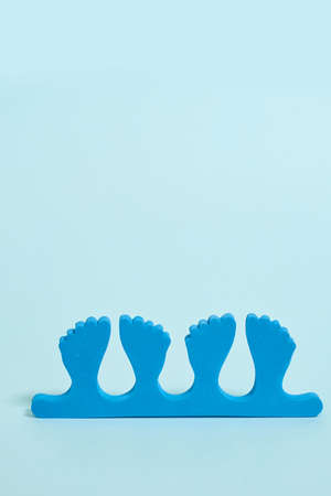 pedicure kit. Finger separators on a blue background. Top view, copy space, vertical format