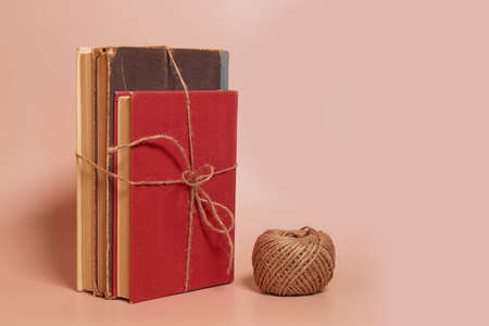 A stack of old battered books tied with jute rope, a coil of jute rope on a colored background. side viewの写真素材