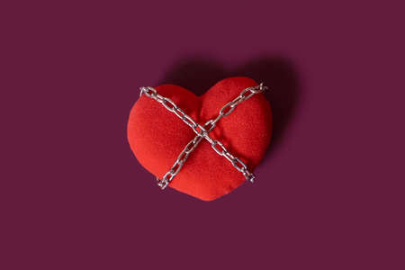 love addiction. A toy heart rewound by a chain on a colored background. Space for textの写真素材