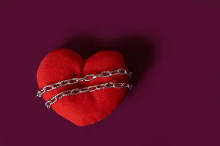 love addiction. A toy heart rewound by a chain on a colored background. copy spaceの写真素材
