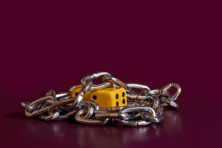 Gambling addiction. Two dice is wrapped with a chain on a colored backgroundの写真素材