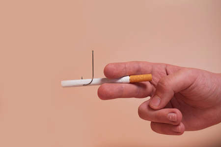 Nicotine addiction. A child's hand holds a cigarette with a fish hookの写真素材