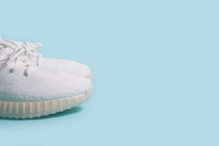 A pair of white sneakers on a blue background. side view, close upの写真素材