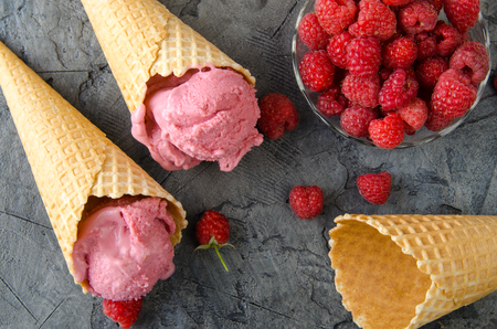 Raspberry ice cream with ice cream cones on stone table.の写真素材