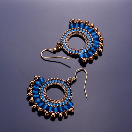 Beaded earrings blue on a dark background. Beadwork. Top view.の写真素材