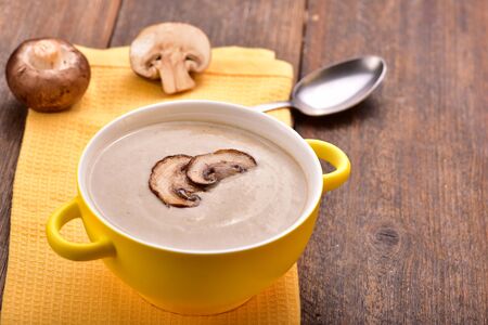 Mushroom cream soup on yellow napkin. Wooden table. Copyspace.の写真素材