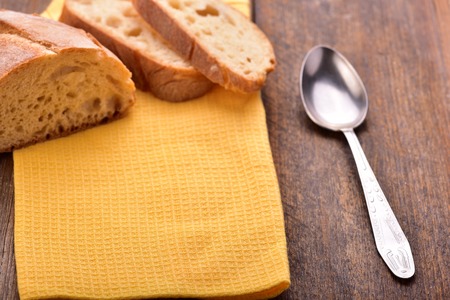 Homemade sliced bread with yellow napkin and spoon on wooden table.の写真素材